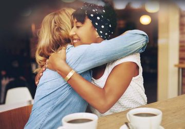 Two women hugging over coffee